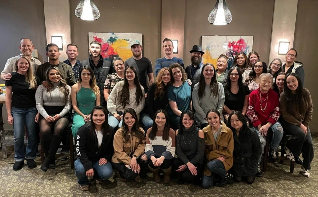 Large group of orthodontics staff and team members posing together in modern office setting with balloons.