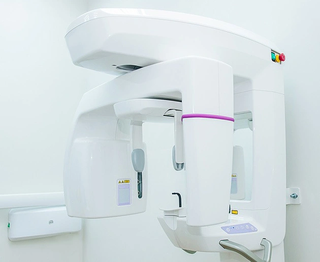 Modern dental panoramic X-ray machine in a clinical treatment room setting.