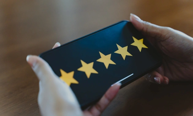 Person holding dark blue wallet with five gold stars displayed against wooden surface.