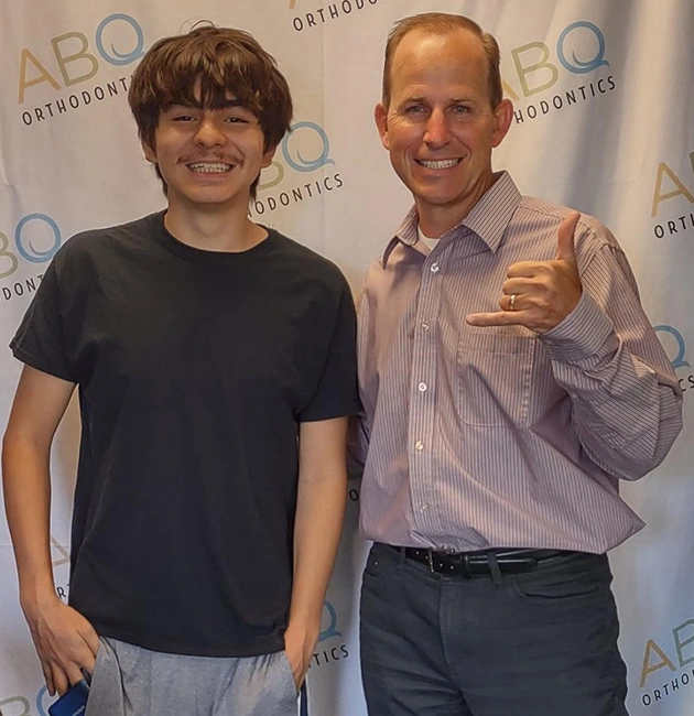 Two people posing together at ABQ Orthodontics event with branded backdrop