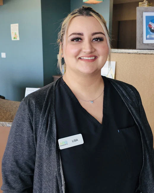 Smiling female orthodontic staff member wearing name badge in modern dental office setting.
